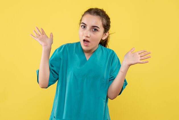 正面黄色墙壁上穿着医疗服的女医生的正视图医院套装刮刀