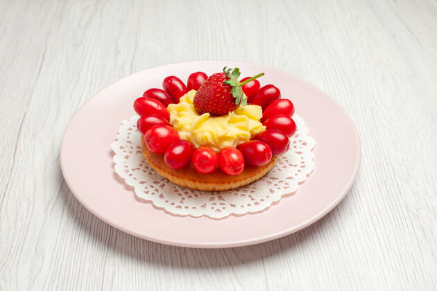 水果前视图美味奶油蛋糕与山茱萸上的白色办公桌蛋糕甜点水果红色盘子新鲜葡萄干