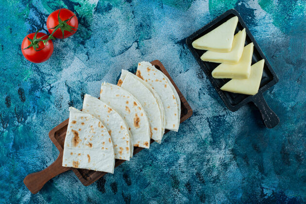 面包在蓝色背景上 在西红柿旁边的板上放上薰衣草和美味的奶酪土耳其玉米饼皮塔