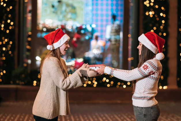 女孩女孩在街上给她的女朋友送礼物女人乐趣圣诞老人