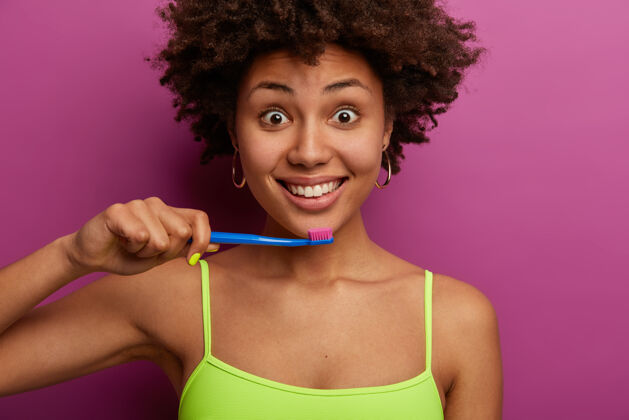 生活方式迷人的卷发女人有牙齿健康的微笑 拿着牙刷人类美白肩膀