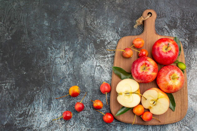 切从远处俯瞰苹果切菜板上开胃的红苹果和樱桃农产品板蔬菜