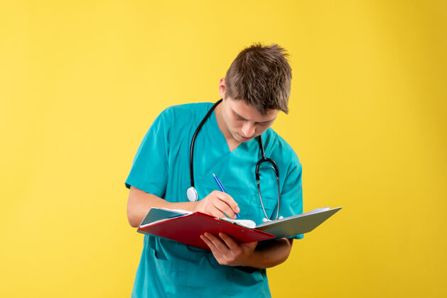 健康黄色墙壁上穿着医疗服的男医生手持分析图的正视图男医生人医院