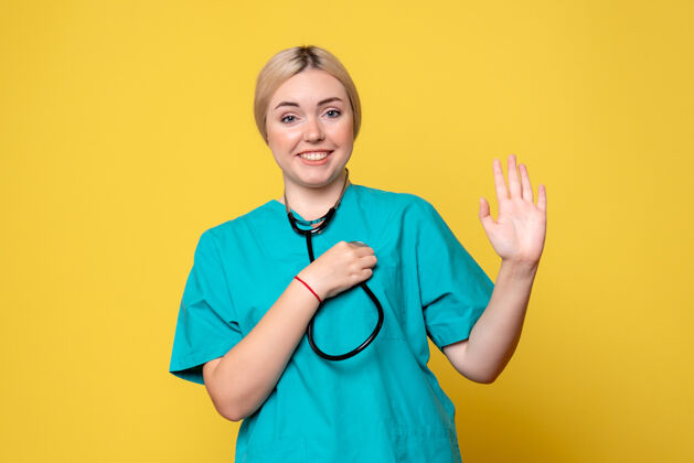 护士黄色墙壁上穿着带听诊器的医用衬衫的女医生的正视图听诊器医疗器械衬衫