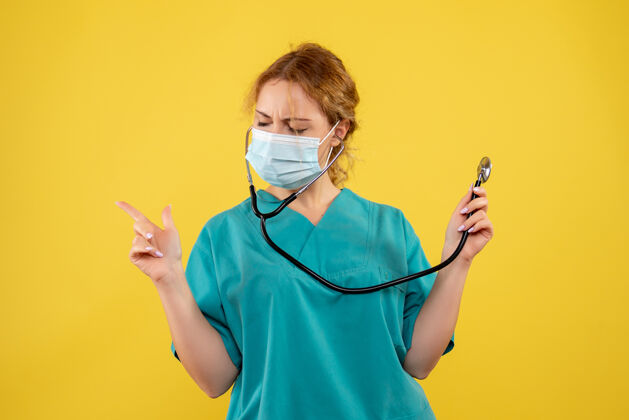 医疗器械黄墙上穿着医疗服 戴着听诊器面罩的女医生的正面图面罩护士女医生