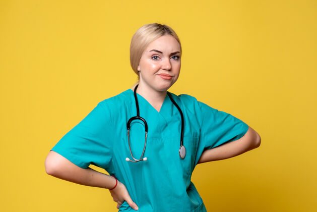 医疗器械黄色墙壁上穿着带听诊器的医用衬衫的女医生的正视图医院女医生器械