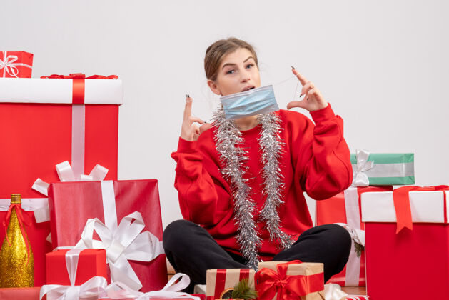 围着正面图：年轻女性戴着无菌面具围坐在圣诞礼物旁礼物年轻女性礼物
