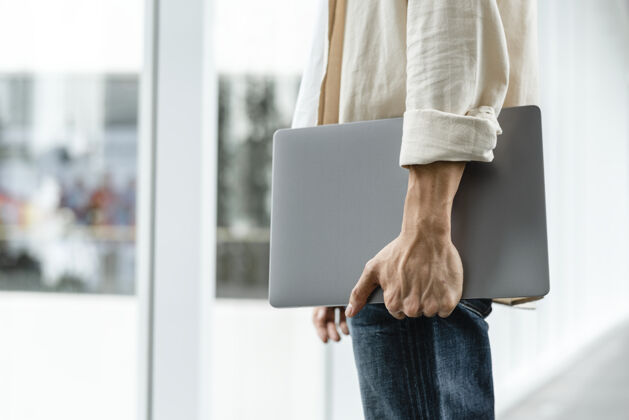 城市一个在城里散步的人拿着他的笔记本电脑人购物中心企业家