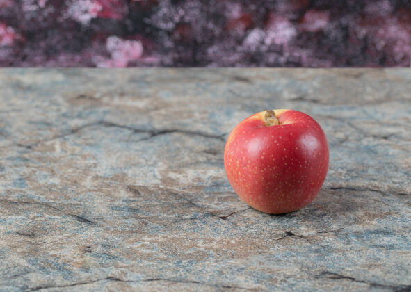 光隔离在混凝土表面的红苹果产品热带异国情调