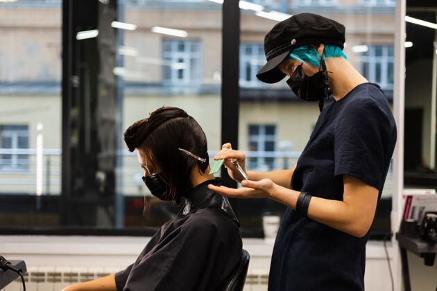 工人一个专业的女理发师给客户理发这个女孩戴着面具坐在美容院里肖像发廊设备