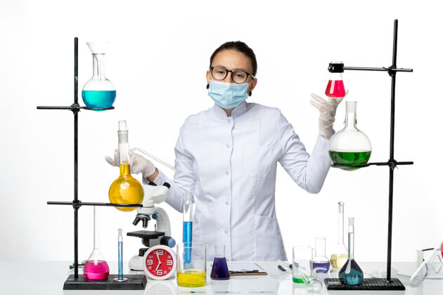 药品前视图：身穿医疗服的女化学家 戴着口罩 站在房间里 白色背景上有解决方案病毒化学实验室covid-飞溅化学里面视图