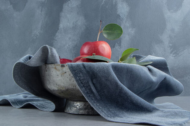 碗一堆苹果放在一个铺着桌布的金属碗里 放在大理石上水果多汁健康