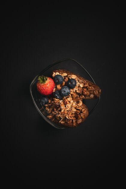 蓝莓垂直拍摄一个玻璃碗健康小吃蓝莓 草莓在一个黑色的桌子上新鲜浆果美味