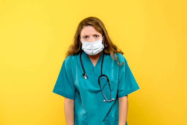 医疗保健黄色墙上戴着无菌口罩的女医生的正视图医疗器械面罩人