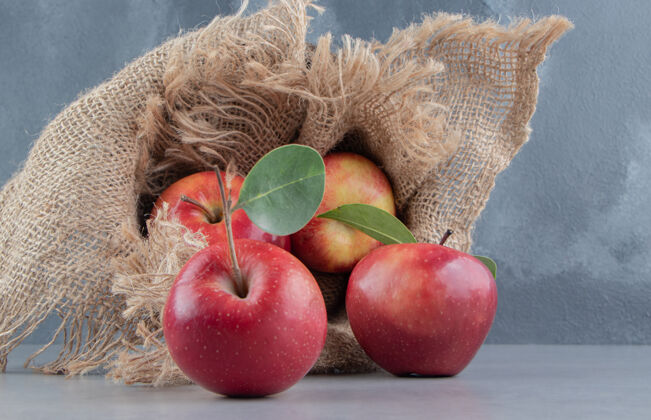 美味新鲜的苹果从覆盖着布的篮子里洒在大理石上健康有机布片