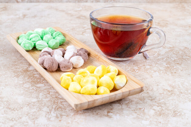 糖果一杯茶和各式各样的糖果装在一个小木托盘里美味小吃糖果