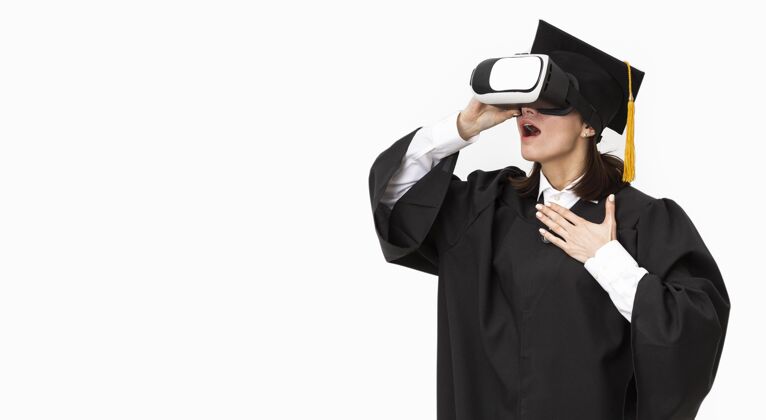 虚拟现实穿着毕业礼服戴毕业帽戴着虚拟现实耳机的女人虚拟现实眼镜仿真毕业帽