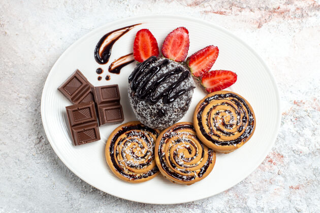 饼干俯瞰美味的饼干与巧克力蛋糕和草莓的白色空间盘子钱饼干