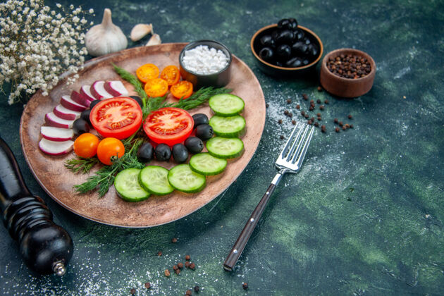 厨房前视图新鲜切碎的蔬菜橄榄盐在一个棕色的盘子和厨房锤子大蒜素花绿黑色混合色背景晚餐午餐食物