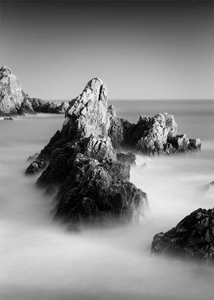地平线格恩西岛岩石海滩的惊人灰度照片垂直白模糊
