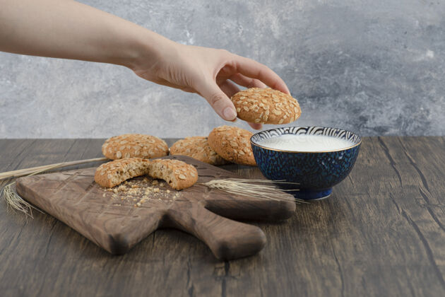 饼干女性手拿着一块美味的燕麦饼干放在木头表面麦片小麦芝麻