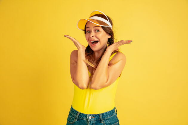 肖像摆出可爱 微笑的姿势黄色工作室背景上的白种女人肖像戴帽子的漂亮女模特人类情感的概念 面部表情 销售 广告夏日 旅游 度假衬衫行政公司