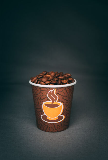 垂直拍摄一个印满烤咖啡豆的杯子隔离在黑暗的墙上咖啡香味清凉