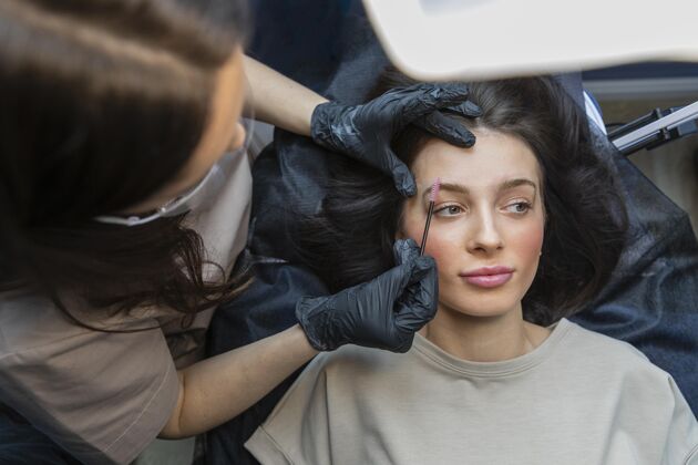 女人美容师正在为她的客户做眉毛护理女人客户美容