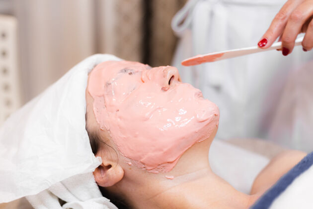 健康美容师用抹刀在女人脸上敷海藻酸钠面膜治疗健康治疗