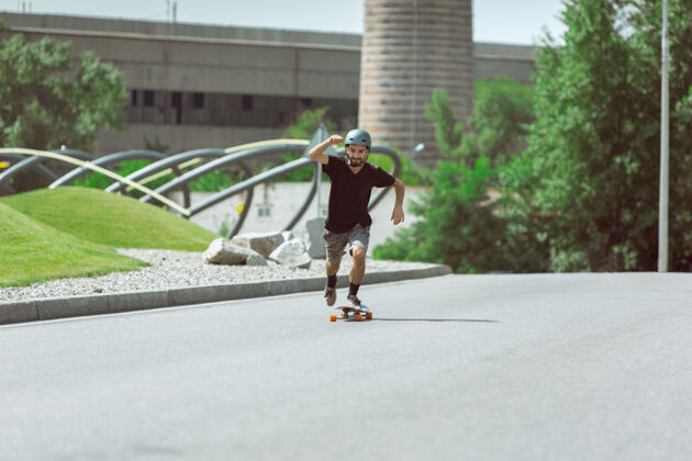 滑板在阳光明媚的日子里 在城市街道上玩滑板的人穿着装备的年轻人在沥青路面上骑行和玩长板休闲活动 运动 极限 爱好和运动的概念公园极限空气