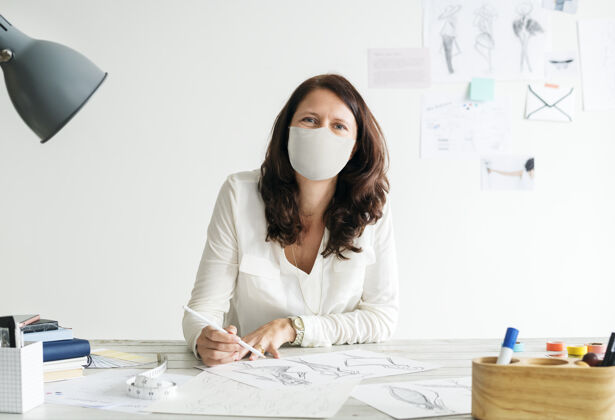 商务女士设计师戴着面具在新的正常办公场所工作铅笔病毒爆发商务人士