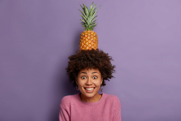 请美丽的快乐女人 非洲式发型 头上抱着新鲜的菠萝和绿叶 摆出夏日水果的姿势水果美味美味