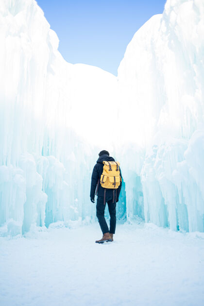 冰川穿着黑色夹克和蓝色牛仔牛仔裤的男人站在雪地上人山背包
