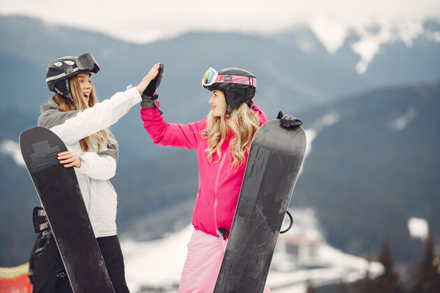 木板穿着滑雪板套装的女人在山上的运动员手拿滑雪板在地平线上关于运动的概念两个护目镜山地
