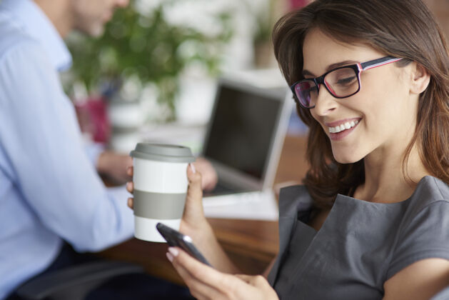 短信喝咖啡和使用手机微笑商务女人现代