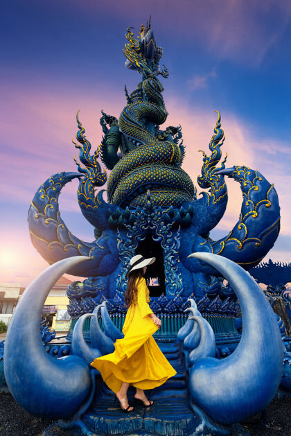 雕像泰国清莱 游客身穿黄色礼服 站在蓝色雕像前亚洲旅游宗教