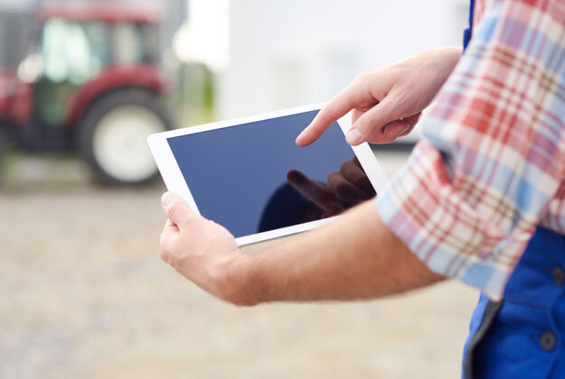 农场年轻的农夫在打理他的生意平板电脑护理商业
