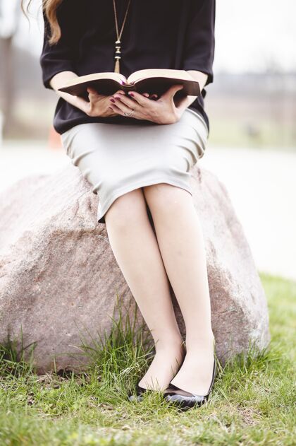 学生一个穿着灰色裙子坐在岩石上看书的女人文学知识漂亮