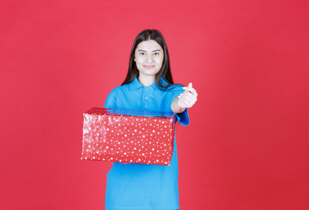 庆祝一个女人拿着一个上面有白点的红色礼盒 要求付款成人年轻礼盒