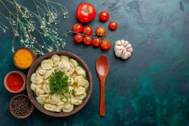 美食俯瞰美味的饺子汤配上不同调味料的深绿色背景汤面团蔬菜肉食观点顶部生的