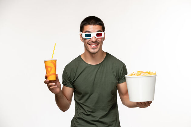 肖像正面图身穿绿色t恤的年轻男性手持土豆cips苏打水in-d太阳镜在白色墙上拍摄电影男性孤独电影电影院电影年轻的男性电影