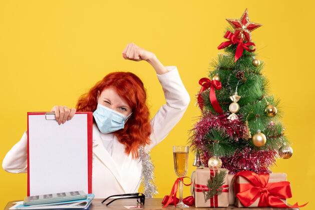 病毒前视图女医生围绕圣诞树和礼物坐在面具年份圣诞到处都是