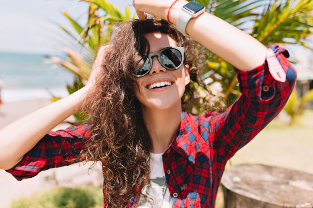 自然兴奋快乐的女人 卷发戴太阳镜 看起来很开心 微笑着暑假海洋人成人
