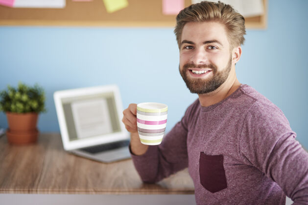 男人喝咖啡和使用笔记本电脑办公桌自由职业者电脑
