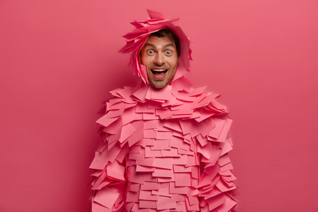男人快乐积极的女人的照片看起来惊奇和快乐 有好玩的心情 笑笑话 做贴纸的纸装 孤立在粉红色的墙上 有搞笑的谈话肖像粘着单色