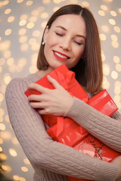 闪亮快乐的年轻女子拿着许多带灯的礼品盒梦幻礼物灯