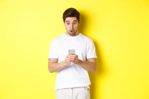 成年人一个穿着白色套装 穿着智能手机 看着手机上的信息 脸上露出惊讶的表情的男人年轻帅气时尚