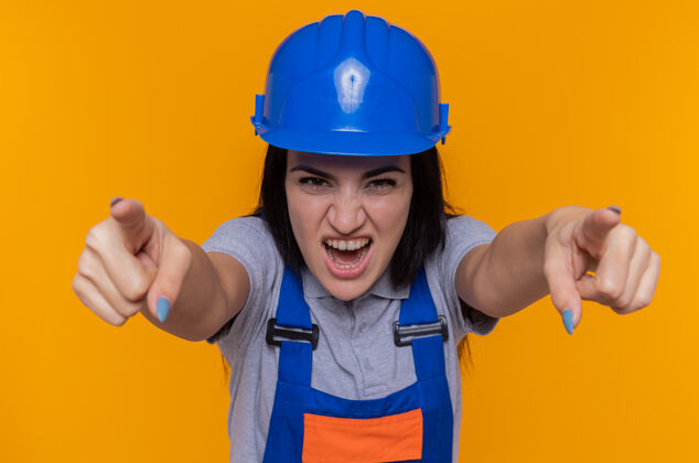 表情穿着施工制服和安全帽的年轻建筑工人建筑制服手指