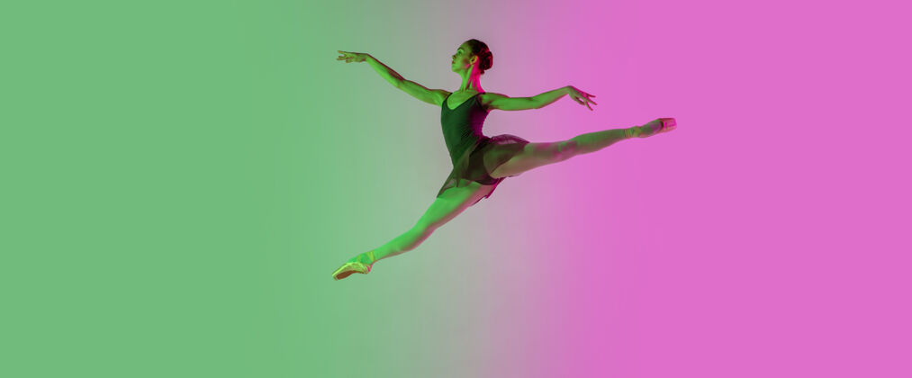 舞蹈轻年轻而优雅的芭蕾舞演员在霓虹灯下被隔离在渐变的粉绿色墙壁上艺术 动作 动作 灵活性 灵感概念灵活的芭蕾舞演员 失重跳跃渐变动作情感