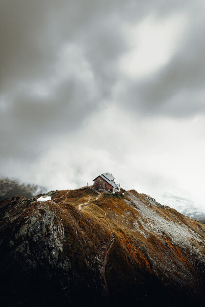 房子白色和棕色的房子在棕色的山顶白云下建筑小屋山